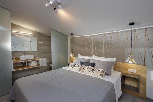 a bedroom with a large white bed and a bathroom at Hermagio Villa George by Estia in Malia