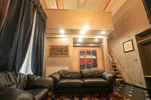 a living room with a leather couch and a staircase at Dimora patrizia in centro in Genova