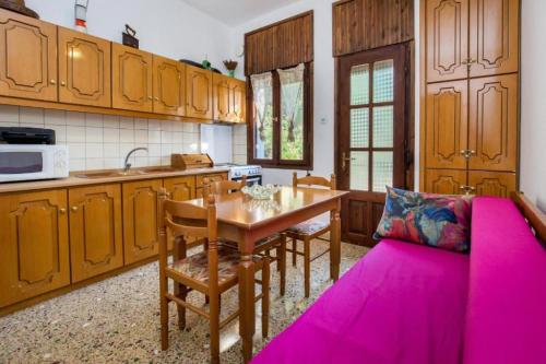 a kitchen with a wooden table and a pink couch at Xanthi's Dream Place in Potos