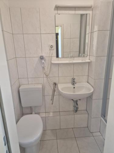 a white bathroom with a toilet and a sink at Hotel Am Stuttgarter Eck in Berlin