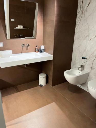 a bathroom with a sink and a toilet and a mirror at Hotel Cave Del Sole in Matera