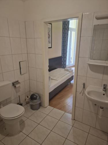 a bathroom with a toilet and a sink and a bed at Hotel Am Stuttgarter Eck in Berlin