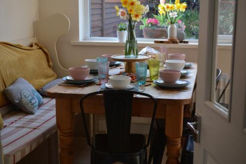 2 Barbour Court في ليسبرن: طاولة مع أطباق وأكواب و إناء من الزهور