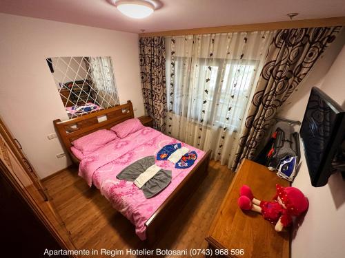 a bedroom with a pink bed and a teddy bear at Apartament frumos cu 3 camere situat la partier in Botoşani