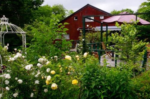 a garden with flowers and a red barn at Gallery HARA and guest house in Hara