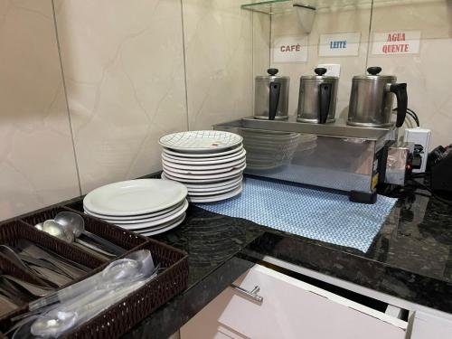 a kitchen counter with a stack of plates and dishes at Hotel Carrão in Sao Paulo