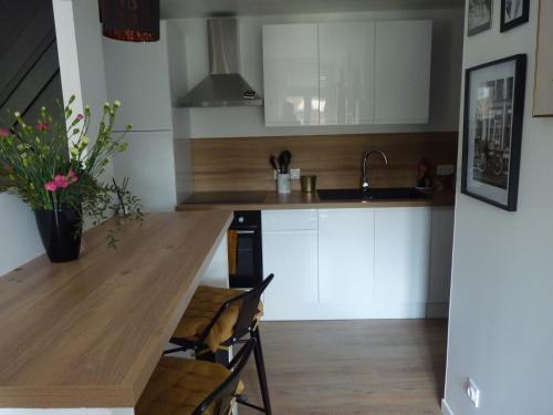 a kitchen with white cabinets and a wooden counter top at Gite Les Matines in Sebourg