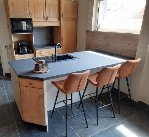 eine Küche mit einem Waschbecken und einer Theke mit zwei Stühlen in der Unterkunft Guesthouse 66 in Lommel