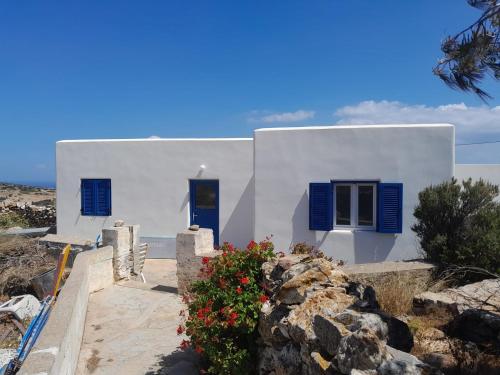 a white house with blue shutters and flowers at Spíti Catharina in Irakleia