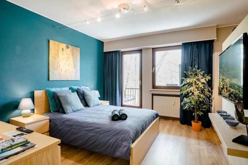a bedroom with a bed with blue walls and a desk at Homestay in a nice flat in Mondorf-les-Bains