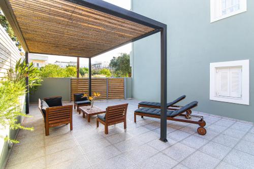 acovered patio with chairs and a table and a bench at Sunshine Studios in Malia