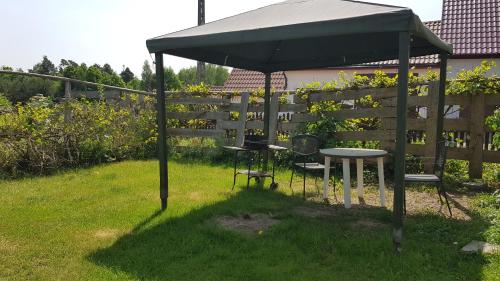 a grill under an umbrella in a yard at Apartamenty Łąkowa Piecki in Piecki