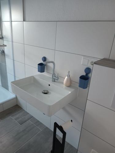 a white bathroom with a sink and a chair at Ferienwohnung Herzberg in Loxstedt