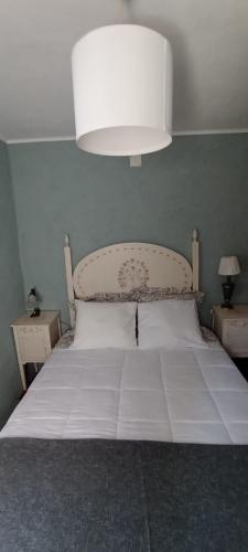 um quarto com uma cama branca e uma grande luz em Cantinho, Alojamento Local no Luso
