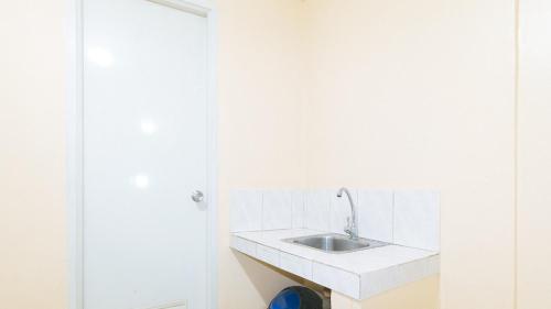 a white bathroom with a sink and a door at Mervin's Terraces by RedDoorz in Manila