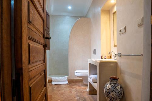 a bathroom with a toilet and a vase next to a door at Riad Le Plein Sud in Marrakech