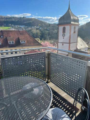a table and chairs on a balcony with a clock tower at Sonniges Ferienapartment am Alten Binauer Schloss in Binau