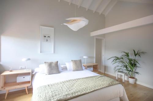 a white bedroom with a bed and a table and plants at Hacienda Los Orovales in Puerto de la Cruz