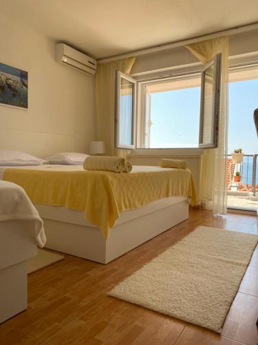 a bedroom with two beds and a window and a rug at House Bartulović in Brela