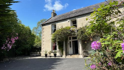 a white brick house with flowers in front of it at Annsborough House Castlewellan in Castlewellan