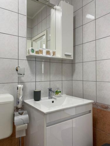 a white bathroom with a sink and a toilet at House Bartulović in Brela