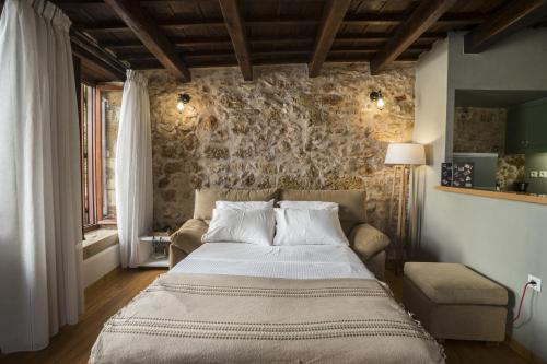 1 dormitorio con cama y pared de piedra en Eulogia Casa, en La Canea