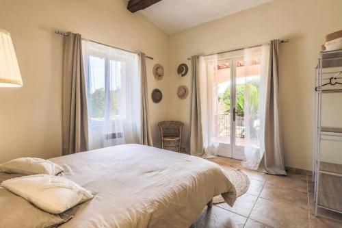 une chambre avec un grand lit et une grande fenêtre dans l'établissement Villa Pastel, à Gassin