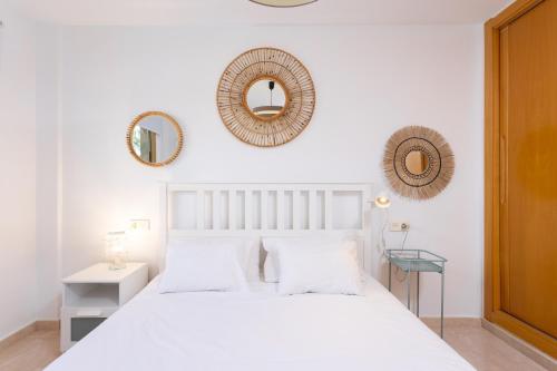 una camera da letto con un letto bianco e specchi sul muro di 110 MEDANO Relax Holiday Home a El Médano