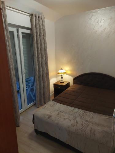 1 dormitorio con cama, lámpara y ventana en Jana apartments, en Tivat