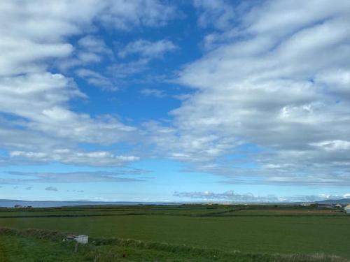a green field with a blue sky and clouds at Luxury holiday rental with sea views on the Wild Atlantic Way in Tralee