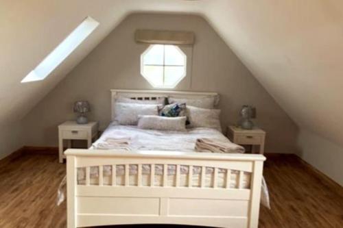uma cama branca num sótão com uma janela em Luxury holiday rental with sea views on the Wild Atlantic Way em Tralee