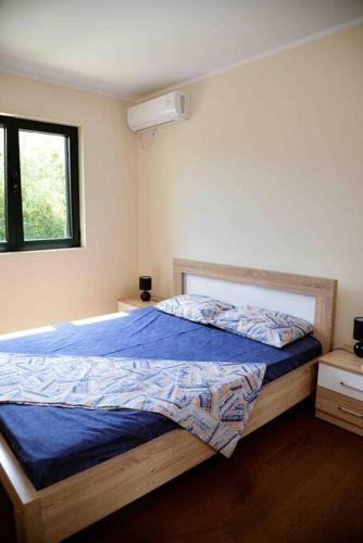 a bedroom with a bed with blue sheets and a window at The Wave in Tivat