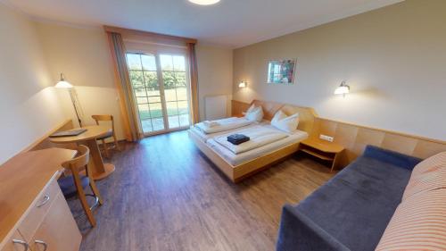 um quarto de hotel com uma cama, uma secretária e uma mesa em Sonntagsberg Hof Familie Fiedler em Bad Waltersdorf