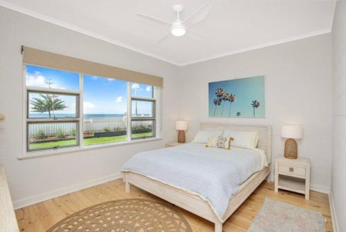 a white bedroom with a bed and two windows at Saltys 4BRM Beachfront WIFI Pet Friendly in Victor Harbor
