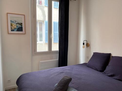 1 dormitorio con cama morada y ventana en Le panier de Clarisse, en Marsella