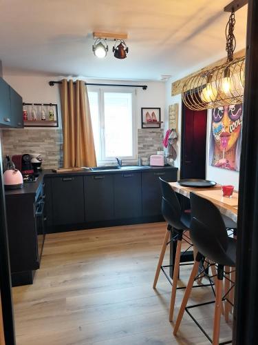 une cuisine avec des armoires noires et une table en bois dans l'établissement Maison Dco Pop Et Chaleureuse Avec Spa, Sauna, à Calais