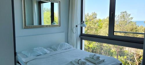 a bedroom with a bed and a window with towels at PINEA Apartments Pobierowo z niesamowitym widokiem na morze oraz jacuzzi w wybranych apartamentach in Pobierowo