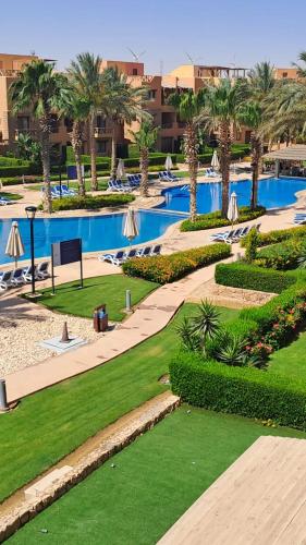 a resort with a swimming pool with palm trees and grass at Luxury Chalet in Mountain View 2 , El-Sokhna with Sea View , Pool View and Garden View Families Only in Ain Sokhna