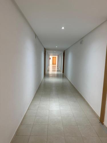 an empty hallway with white walls and a tile floor at Lujoso aprtamento cap tingis playa tanger in Tangier