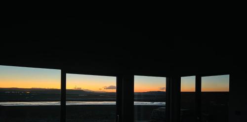 a view of the sunset from a room with windows at Luxury villa with hot tub & amazing view in Reykholt