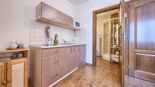 cocina con armarios de madera, fregadero y puerta en VisitZakopane - City Apartments, en Zakopane