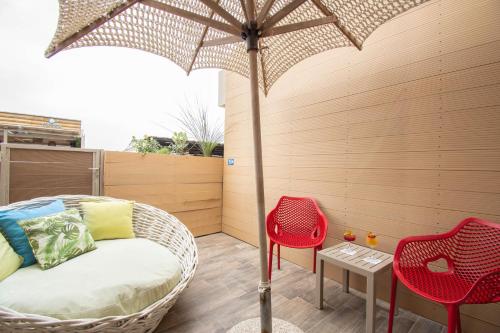 a patio with a wicker bed and chairs and an umbrella at Yianna Caravel Suites "by Checkin" adults only in Amoudara Herakliou