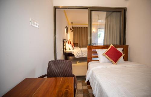 a hotel room with two beds and a table and chair at The Woodside Inn in Benaulim