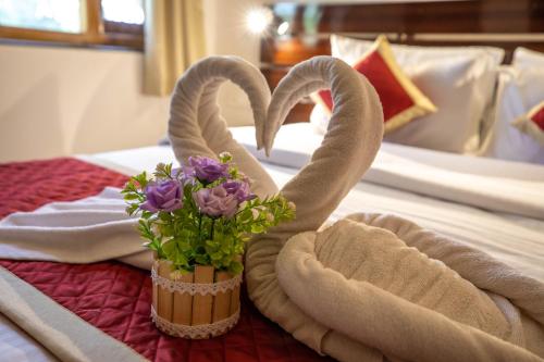 a bed with two towels and a bouquet of flowers at The Woodside Inn in Benaulim