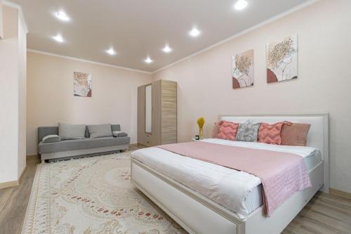 een slaapkamer met een groot bed en een bank bij Апартаменты в ЖК Only Sun - 3 in Astana