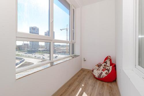 een lege kamer met een rode stoel voor een raam bij Апартаменты в ЖК Only Sun - 3 in Astana