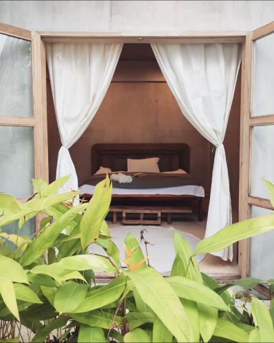 a bedroom with a bed in a room with plants at Prana Siargao Resort in General Luna