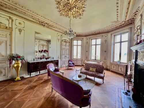 een grote woonkamer met een kroonluchter en een bank bij Chateau les Villettes in Saint-Just-le-Martel