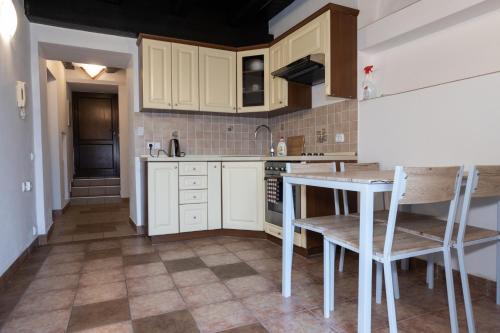 eine Küche mit weißen Schränken sowie einem Tisch und Stühlen in der Unterkunft Apartments 2 in the historic part of Znojmo in Znojmo