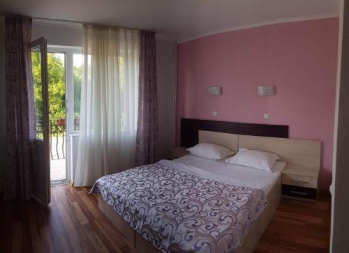 een slaapkamer met een groot bed met roze muren bij Vila Roxana in Sînmartin